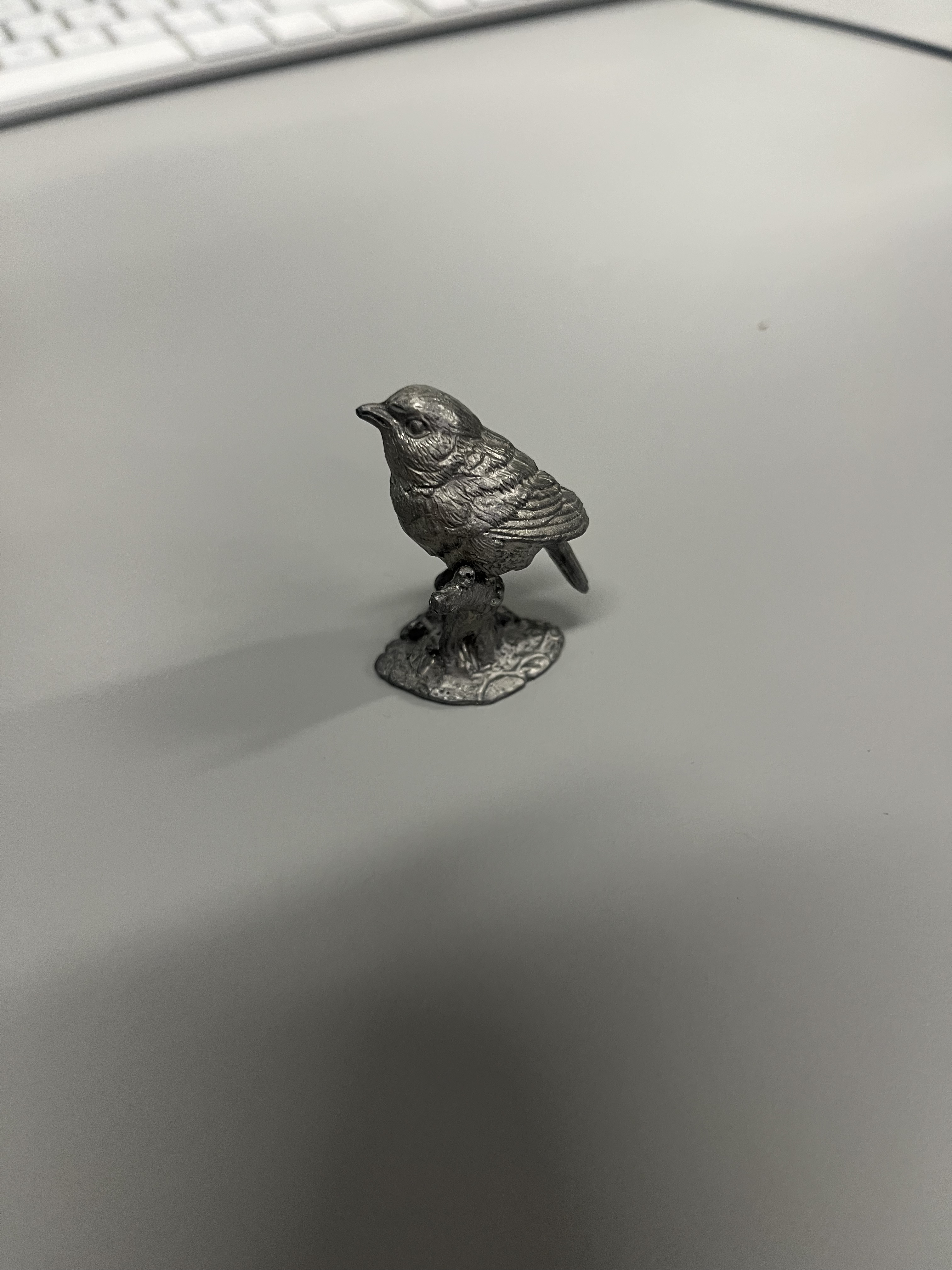 Metal bird <br> Descriptives: Metallic material, carved surface details, silver-gray color.<br>Material State: refined, processed<br>Material Plasticity: rigid<br>Material Use: decoration, handicraft